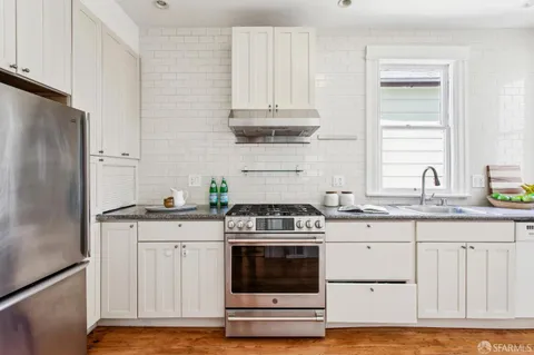 a kitchen with granite countertop white cabinets and stainless steel appliances