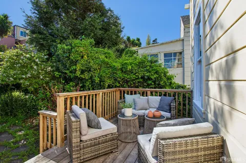 a view of a chair and table in backyard with potted plants and large trees