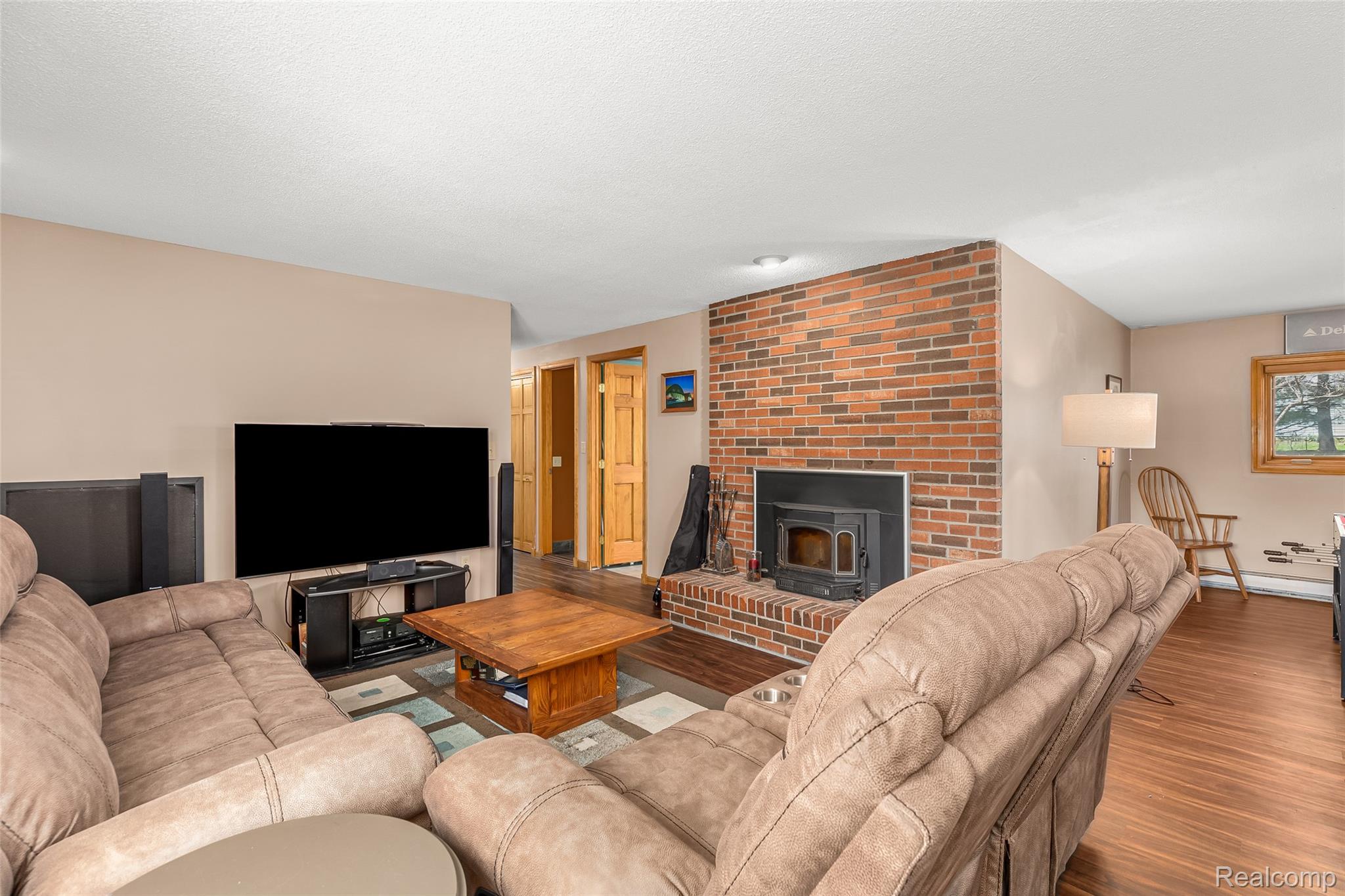 15395 Osius Road Chelsea, MI 48118 - Photo 22 of 55 Spacious living area featuring a prominent brick fireplace with a wood-burning insert