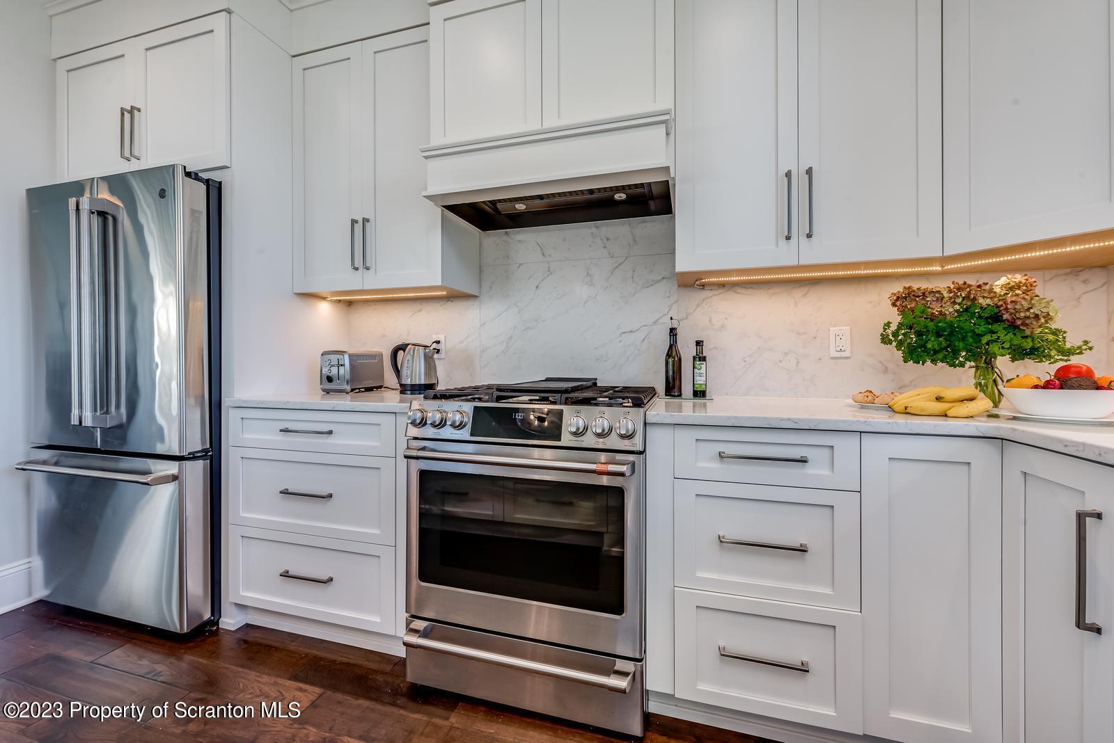 115 Rock Ridge Drive Clarks Summit, PA 18411 - Photo 18 of 43 a kitchen with stainless steel appliances white cabinets and a stove a refrigerator with wooden floor
