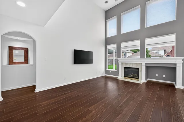 an empty room with wooden floor a fireplace and windows