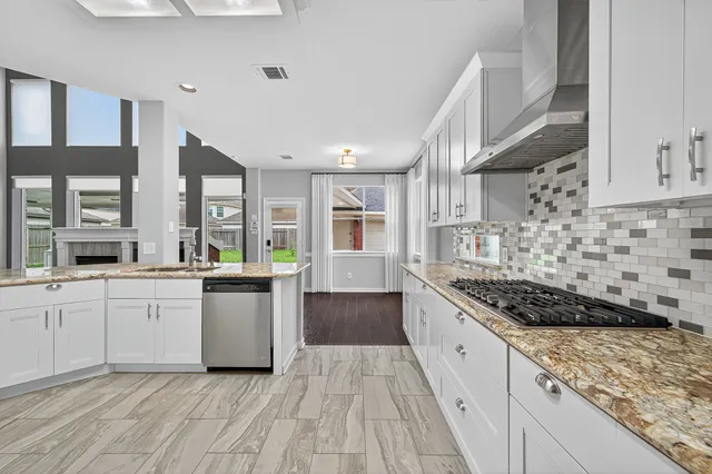 a kitchen with stainless steel appliances granite countertop a stove and white cabinets