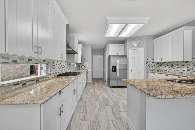 a large kitchen with granite countertop a sink and cabinets