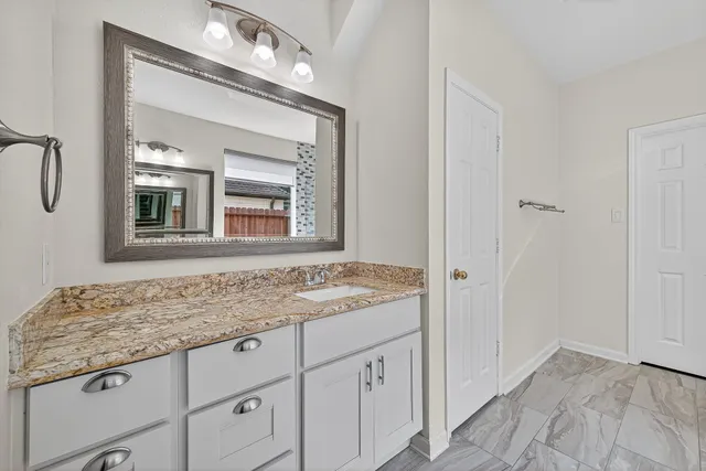 a bathroom with a granite countertop sink and a mirror