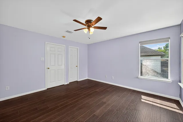 a view of an empty room with window and wooden floor