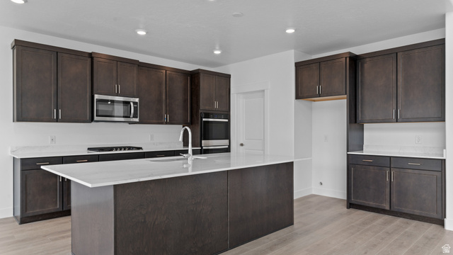 4170 North 560th West, Unit 6 Tooele, UT 84074 - Photo 3 of 20 Contemporary kitchen featuring dark wood-finish cabinetry, light stone countertops, and wood-finish flooring