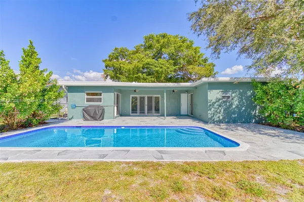 a view of house with swimming pool and yard