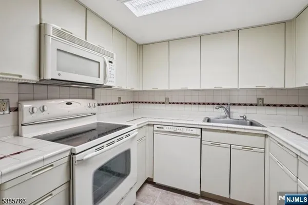 a kitchen with white cabinets and white appliances