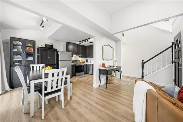 a kitchen with stainless steel appliances kitchen island granite countertop a refrigerator a stove a dining table and chairs with wooden floor