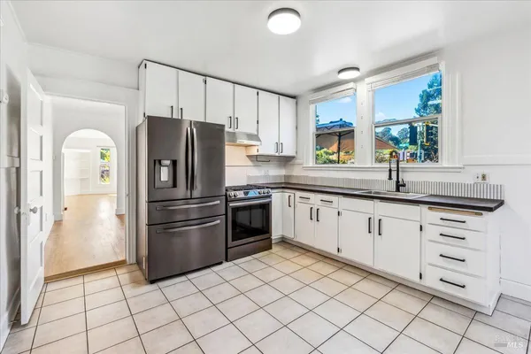 a kitchen with granite countertop a refrigerator and a stove top oven