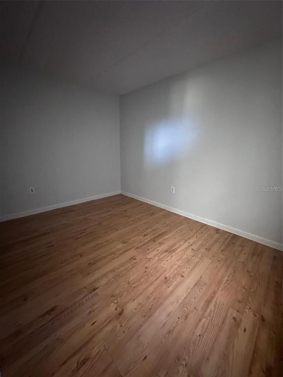 525 South Conway Road, Unit 54 Orlando, FL 32807 - Photo 12 of 16 an empty room with wooden floor and windows