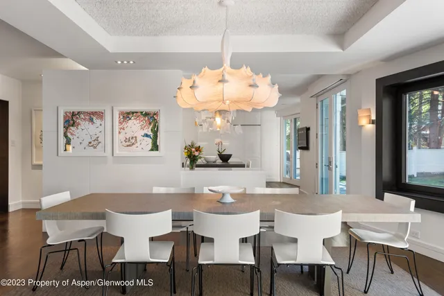 a dining room with wooden floor a chandelier a wooden table and chairs