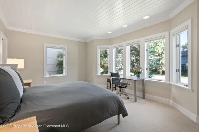 a bed sitting in a spacious bedroom next to a window