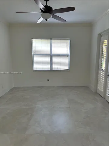 an empty room with a ceiling fan and windows