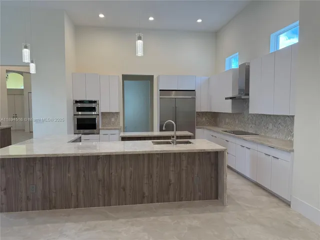 a kitchen with kitchen island granite countertop a sink and stainless steel appliances