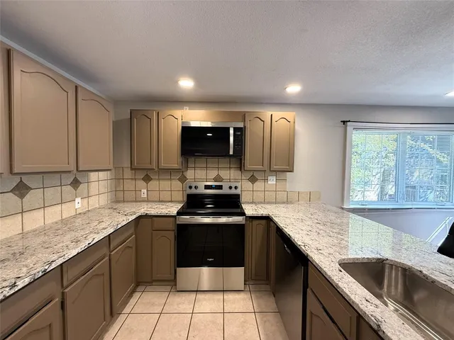 a kitchen with stainless steel appliances granite countertop a sink stove and cabinets