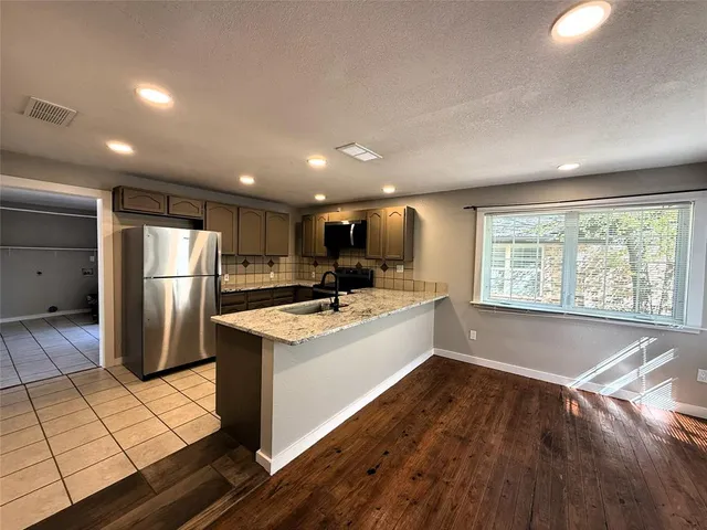 a kitchen with stainless steel appliances granite countertop a refrigerator a sink a stove and a refrigerator