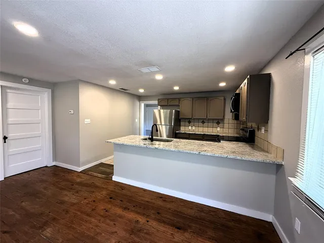 a view of kitchen with stainless steel appliances granite countertop a refrigerator and a sink