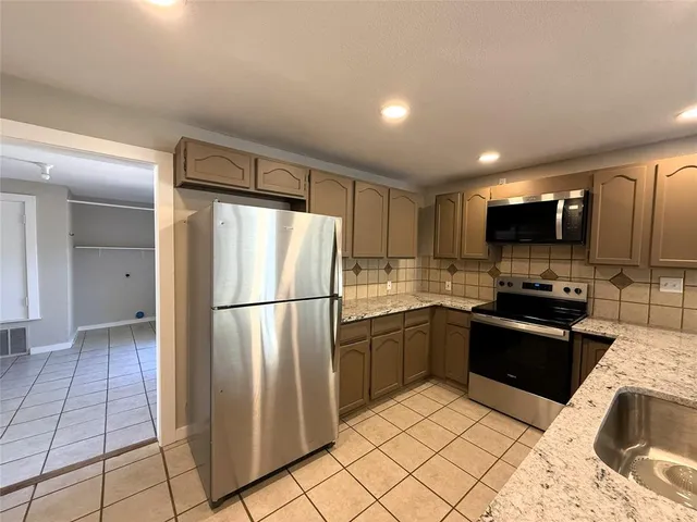 a kitchen with stainless steel appliances granite countertop a refrigerator and a sink