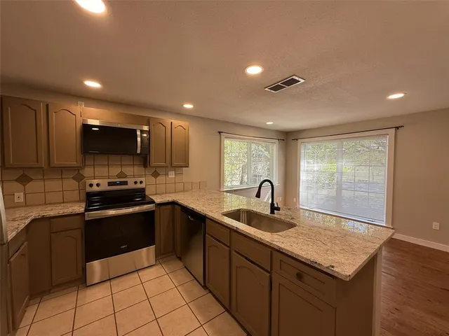 a kitchen with stainless steel appliances granite countertop a sink stove and cabinets
