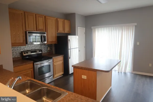 a kitchen with granite countertop wooden cabinets a stove a sink and a oven with wooden floor