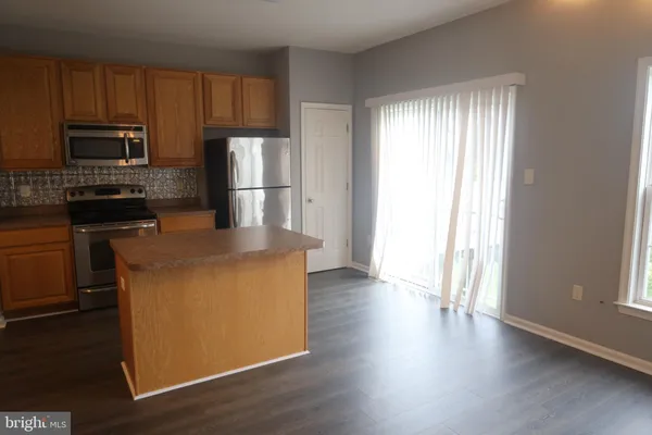 a kitchen with stainless steel appliances granite countertop a refrigerator a sink a stove a microwave and wooden floor