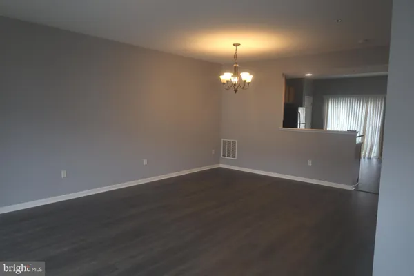 an empty room with wooden floor chandelier fan and windows