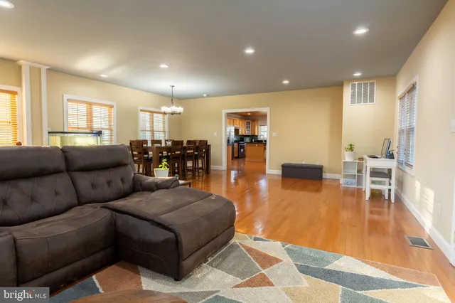 a living room with furniture and a dining table with wooden floor