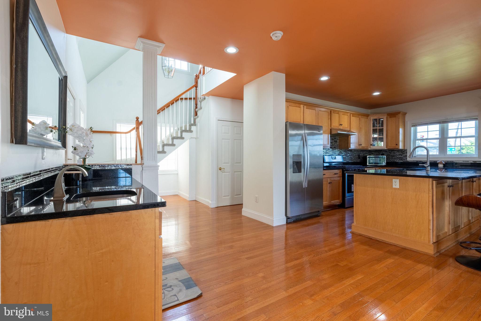 25325 Woodfield Road Damascus, MD 20872 - Photo 31 of 58 a kitchen with stainless steel appliances granite countertop a refrigerator a stove and a sink with wooden floor