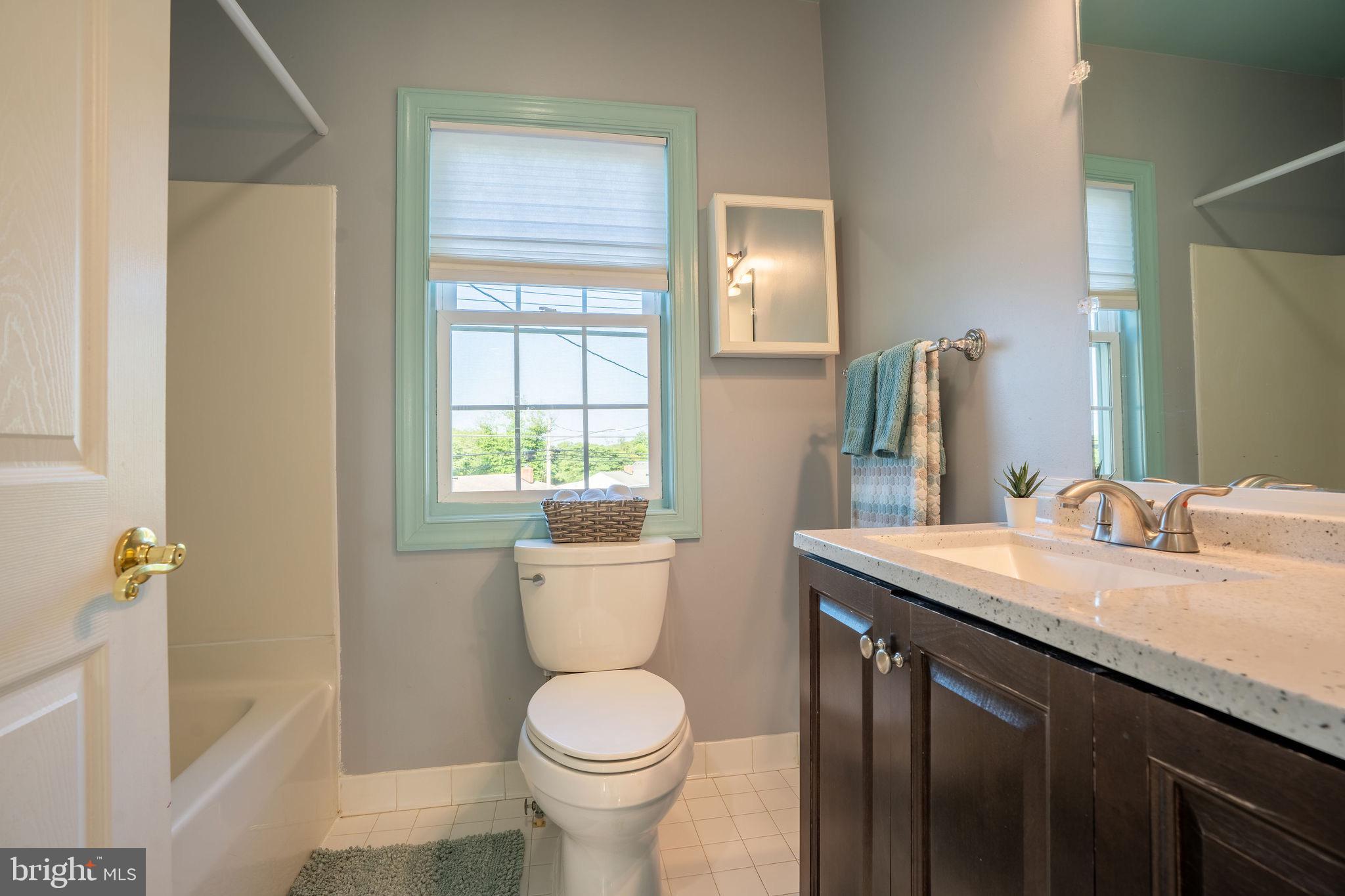 25325 Woodfield Road Damascus, MD 20872 - Photo 48 of 58 a bathroom with a granite countertop toilet a sink and a mirror