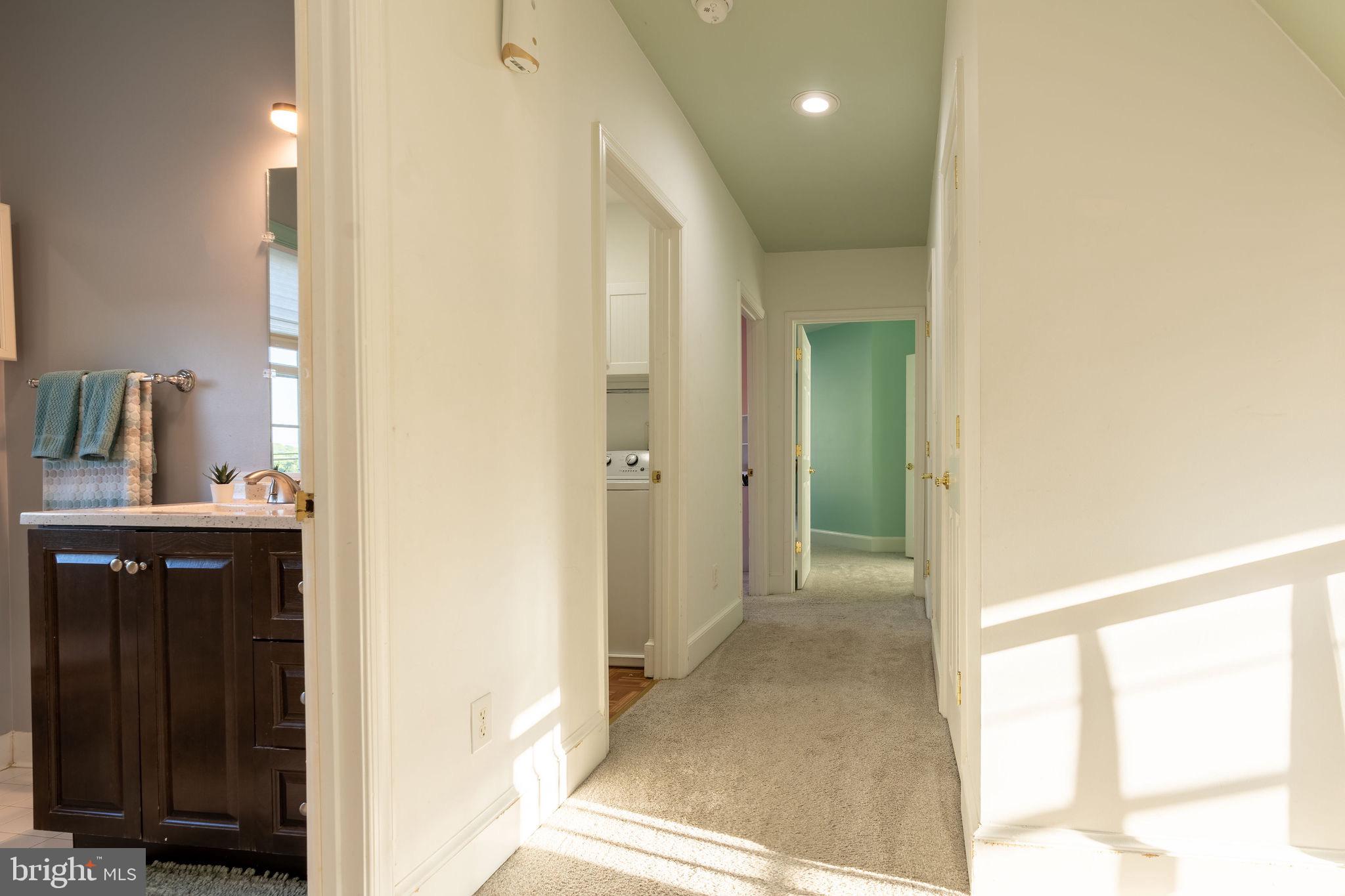 25325 Woodfield Road Damascus, MD 20872 - Photo 49 of 58 a view of a hallway with wooden floor and a bathroom