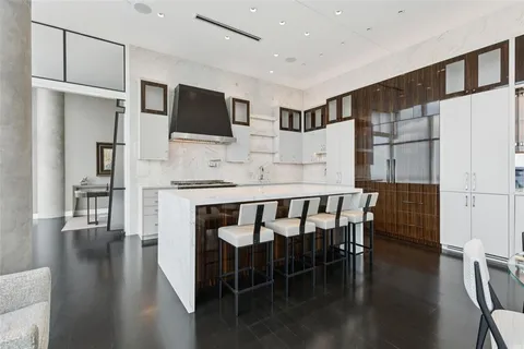 a kitchen with stainless steel appliances granite countertop a stove a refrigerator a microwave a dining table and chairs with wooden floor