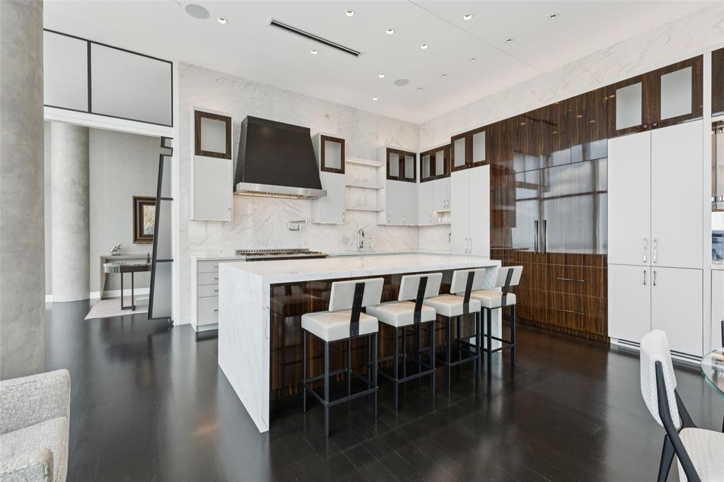 1918 Olive Street, Unit 4202 Dallas, TX 75201 - Photo 12 of 37 a kitchen with stainless steel appliances granite countertop a stove a refrigerator a microwave a dining table and chairs with wooden floor