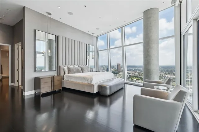 a spacious bedroom with a large window and a wooden floor