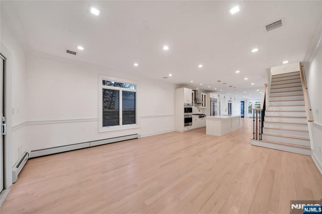 516 Undercliff Avenue Edgewater, NJ 07020 - Photo 11 of 32 a view of an empty room with wooden floor and a kitchen