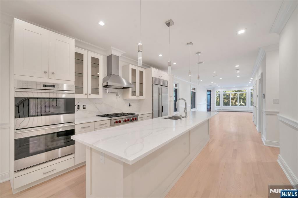 516 Undercliff Avenue Edgewater, NJ 07020 - Photo 9 of 32 a large white kitchen with a stove a sink dishwasher and a refrigerator with wooden floor