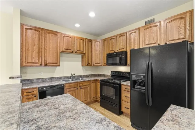 a kitchen with stainless steel appliances granite countertop a refrigerator stove top oven and sink