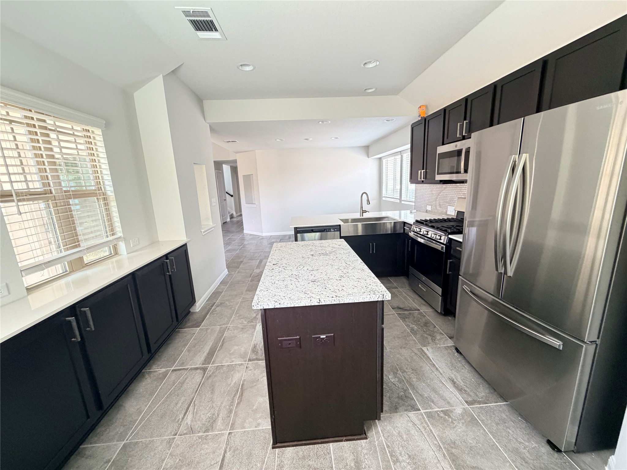 2813 Hopi Path, Unit 11 Leander, TX 78641 - Photo 2 of 17 Kitchen featuring stainless steel appliances, a kitchen island, light stone countertops, a peninsula, and dark cabinets