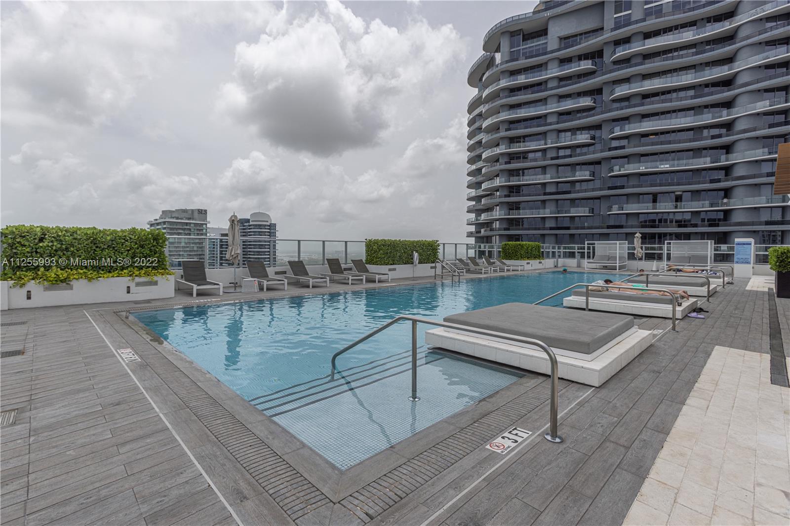 1010 Brickell Avenue, Unit 3003 Miami, FL 33131 - Photo 24 of 32 a view of a swimming pool with outdoor seating and buildings in the background