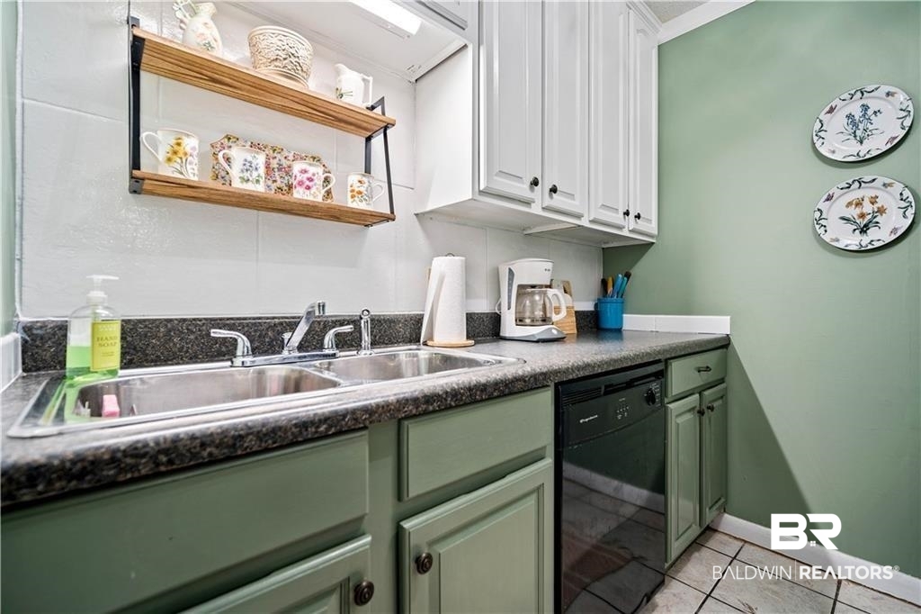 Kitchen with sink, white cabinetry, black dishwasher, and light tile patterned flooring