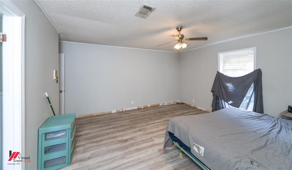 423 11th Street Northeast Springhill, LA 71075 - Photo 22 of 24 Spacious room featuring wood-finish flooring, light gray walls, a textured ceiling, a ceiling fan with integrated lighting, and a white-framed window