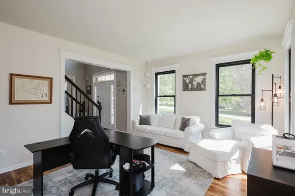 a living room with couches a coffee table and next to a window with wooden floor