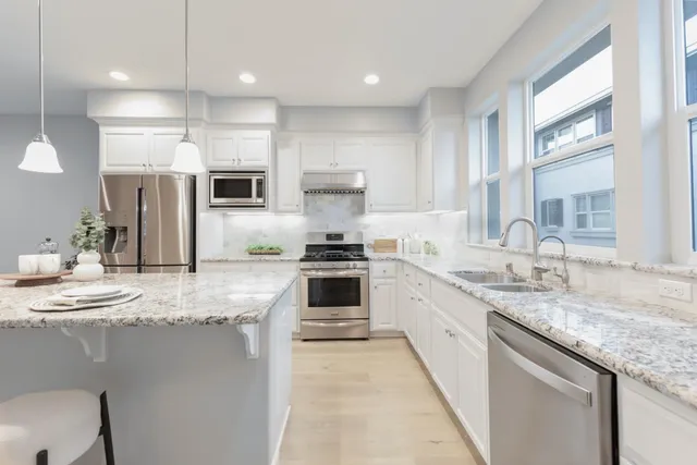 a large kitchen with granite countertop a large counter top appliances and cabinets