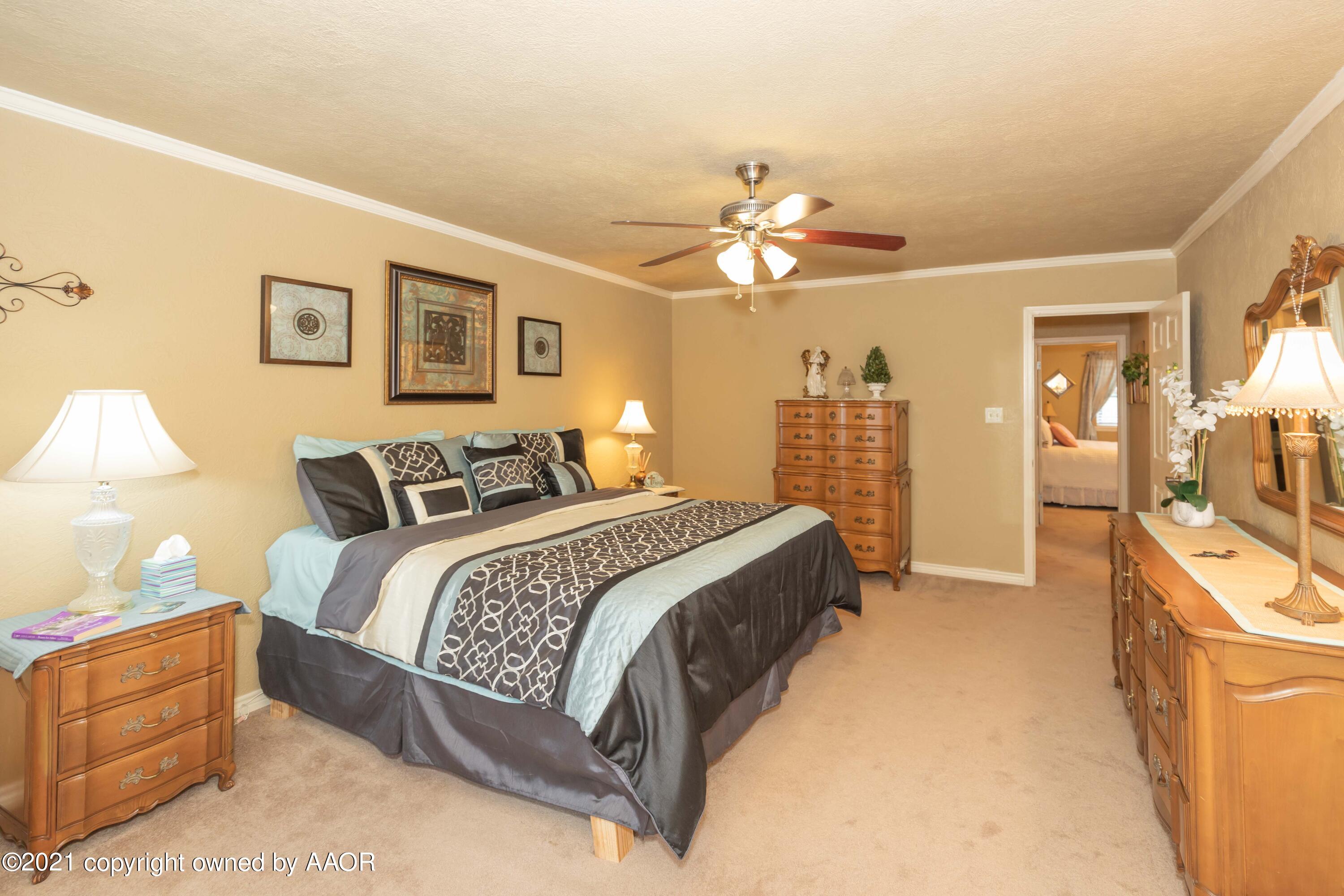 4707 Journey Street Amarillo, TX 79110 - Photo 47 of 65 a spacious bedroom with a bed and a chandelier