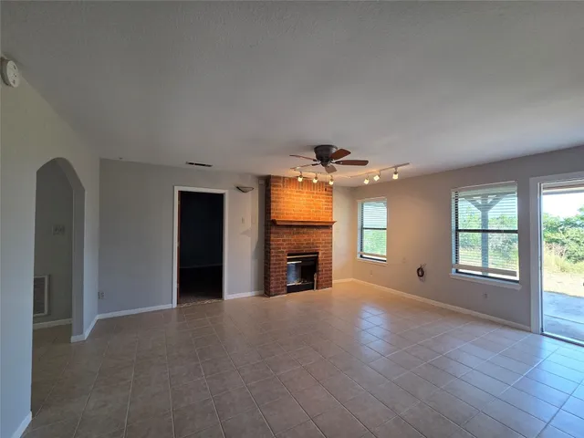 an empty room with windows and fireplace