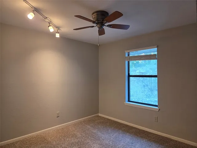 an empty room with a window and a fan