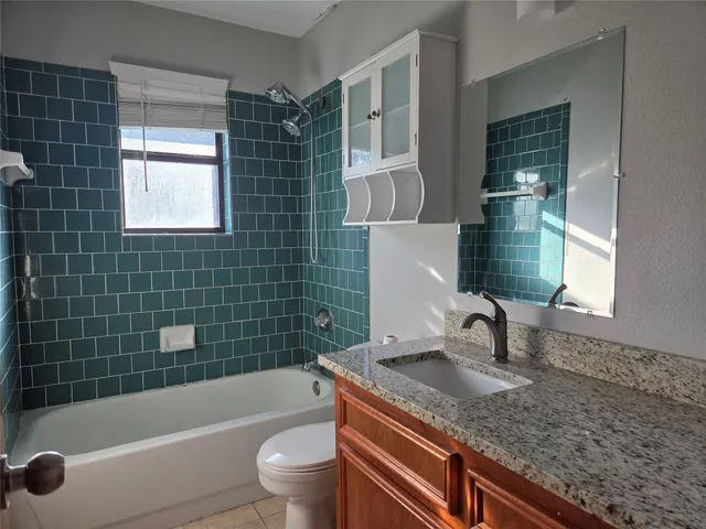 a bathroom with a granite countertop sink a toilet a bathtub and shower