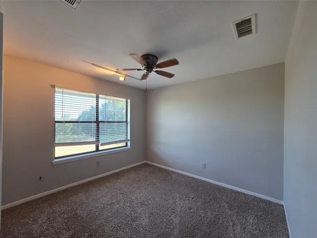 an empty room with windows and ceiling fan