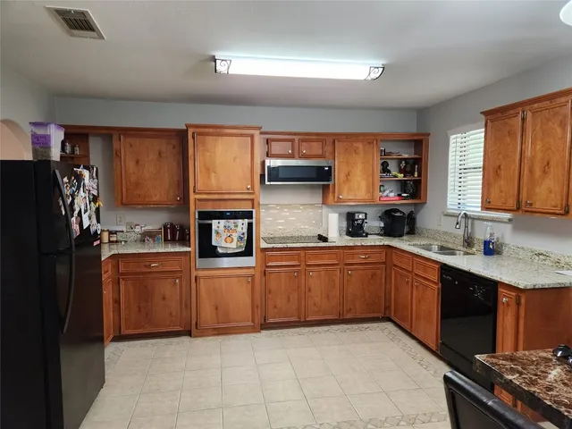 a kitchen with stainless steel appliances granite countertop a refrigerator and a stove top oven