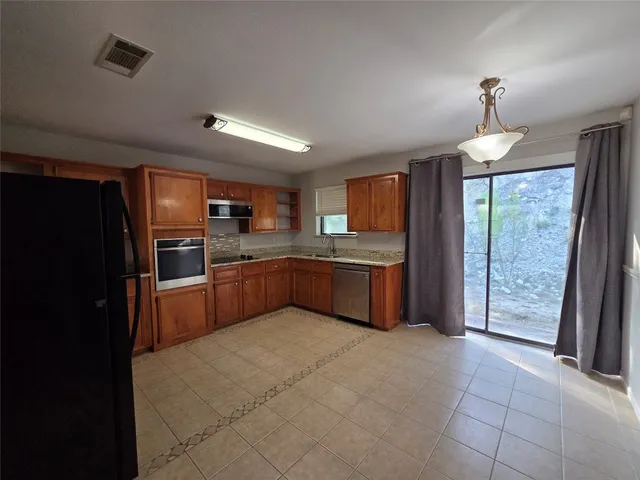 a kitchen with stainless steel appliances kitchen island granite countertop a refrigerator and a stove top oven